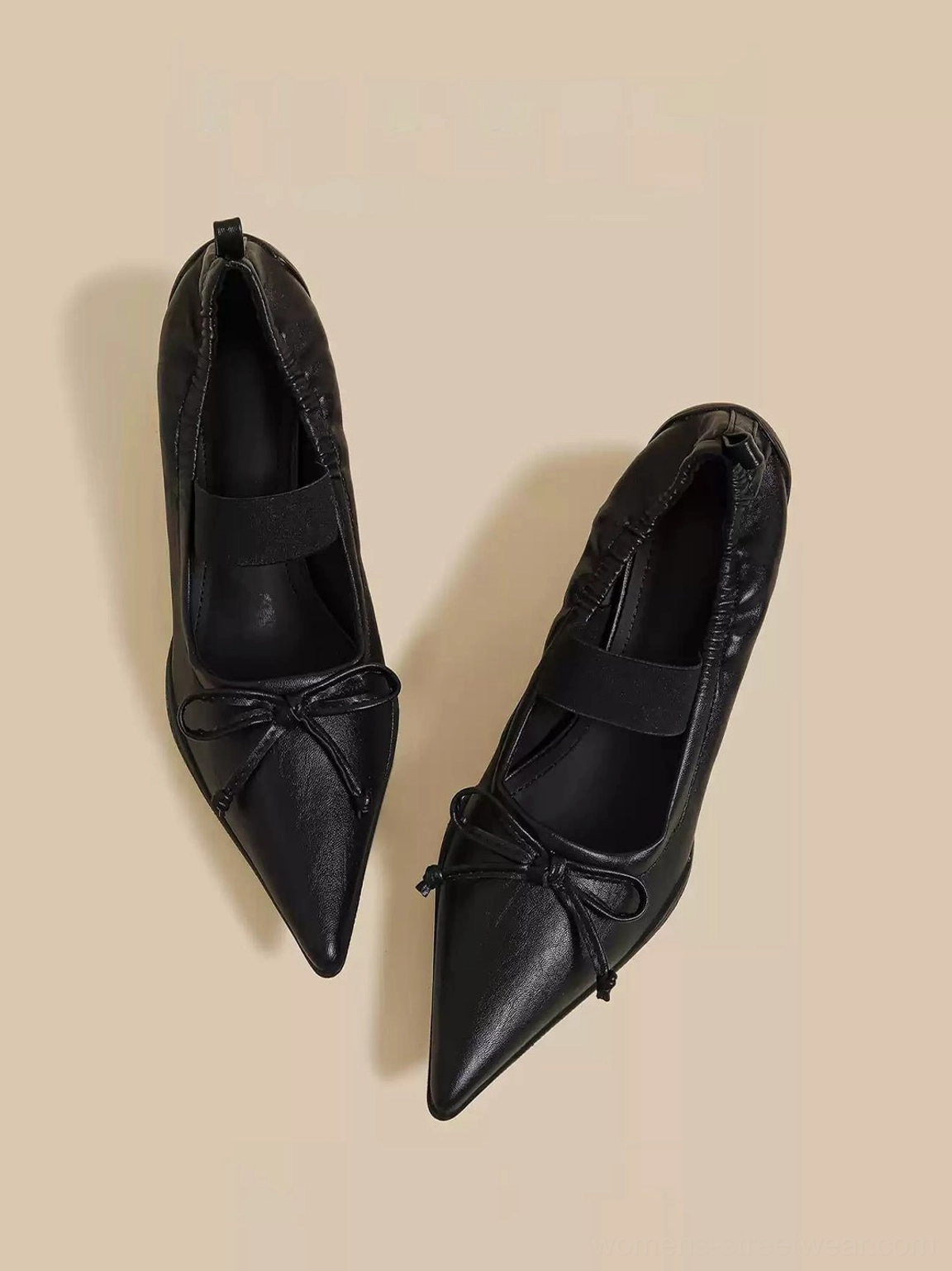 Angled top view of black pointed-toe bow mules showing the pleated upper and sculpted heel shape