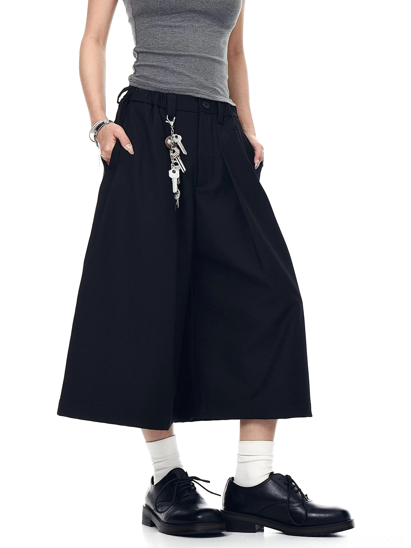 Black pleated wide-leg culotte trousers shown from the front with side pockets, cropped hem, and metal keychain streetwear detail