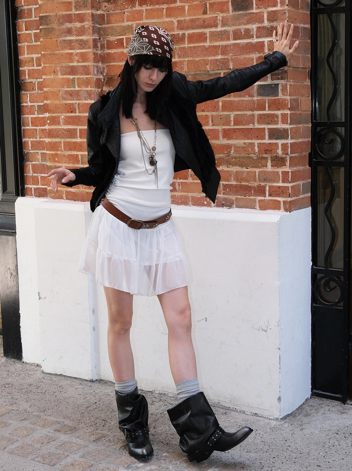Black pointed toe chunky ankle boots styled with white mini skirt and black jacket on city street