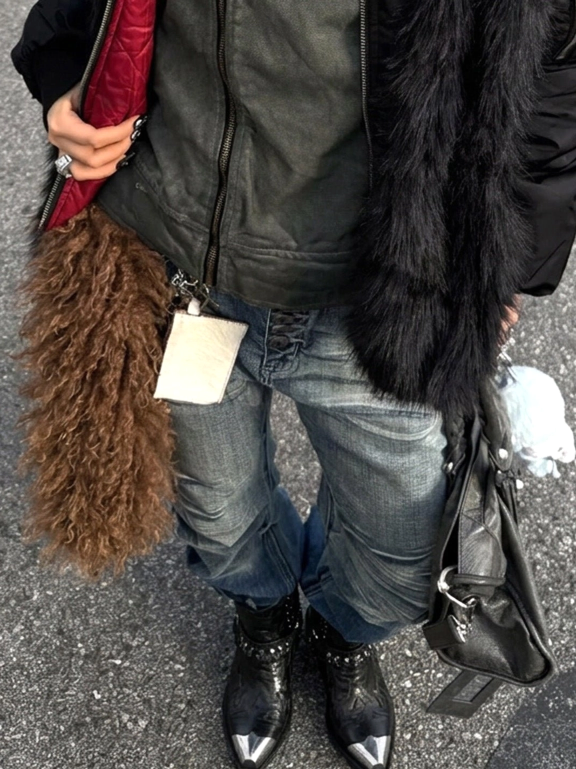 Model wearing matching black pointed-toe western Chelsea boots with silver toe caps and layered heels in a streetwear outfit