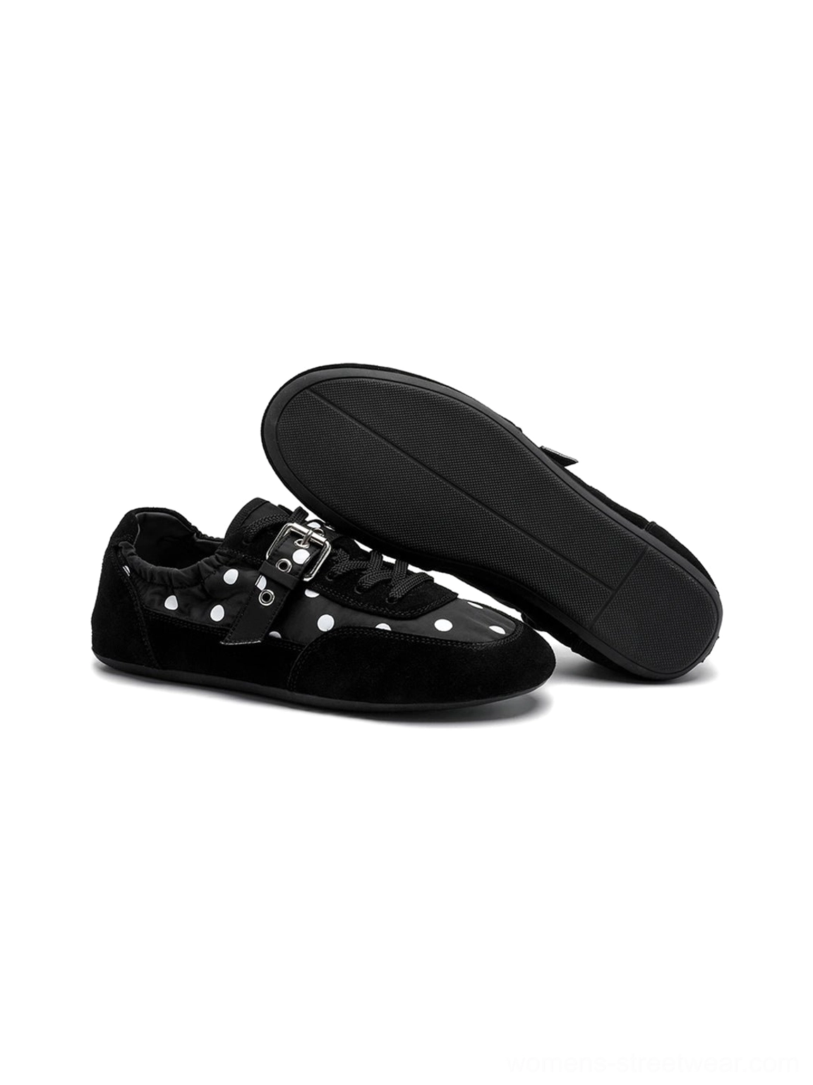 Overhead side view of black polka dot ballet sneakers showing the patterned upper, silver buckle, and flat outsole