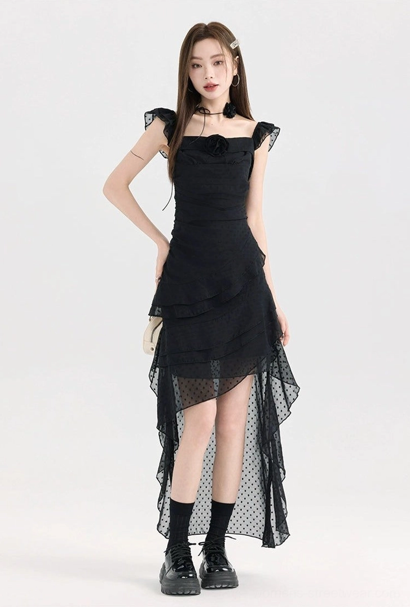 Black polka dot mesh ruffle high-low dress shown in a full-body three-quarter view with square neckline, floral chest detail, asymmetrical sheer tulle hem, and platform boots
