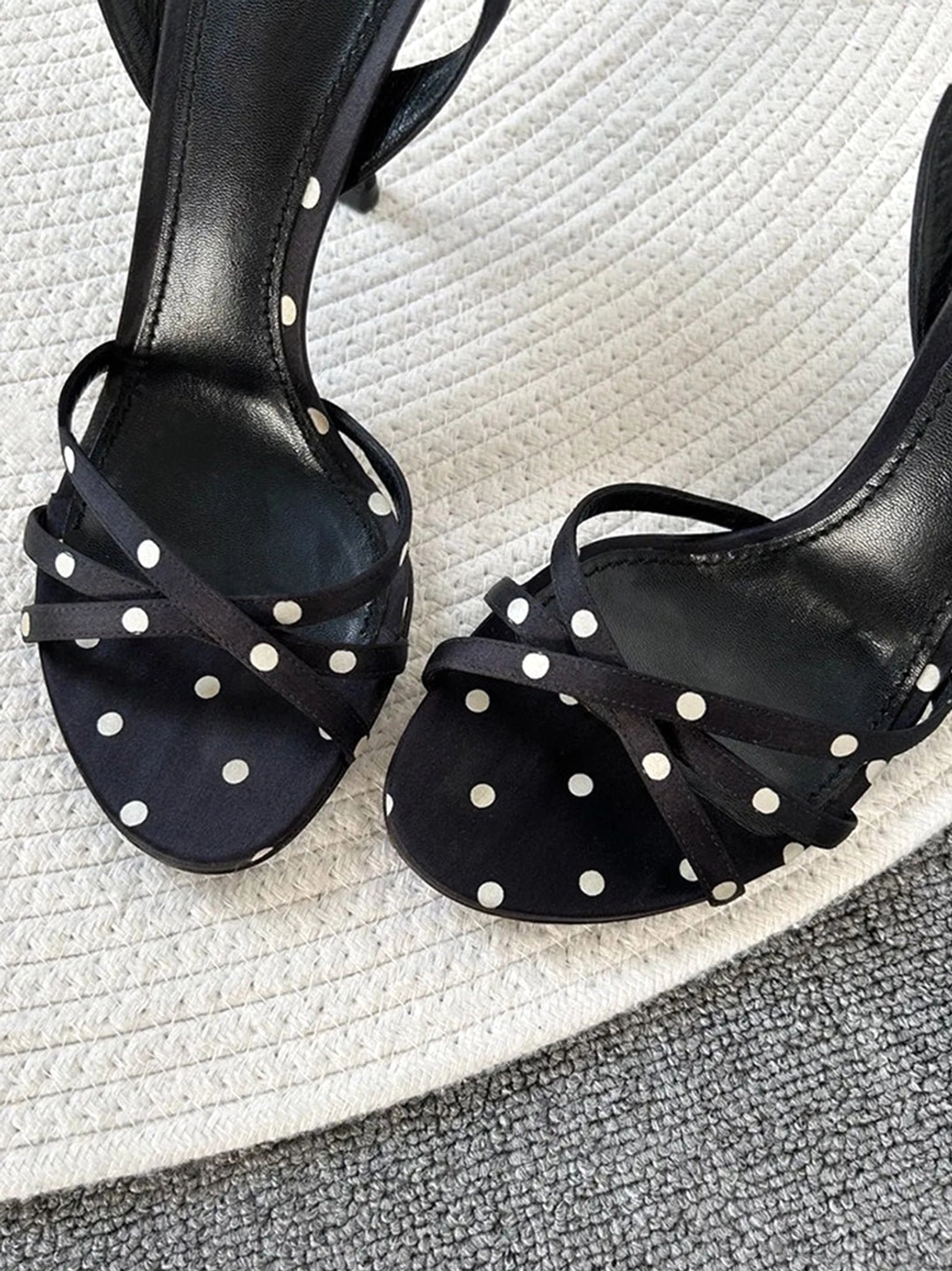 Pair of black polka dot strappy stiletto sandals shown in overhead flat lay with crisscross open toe straps