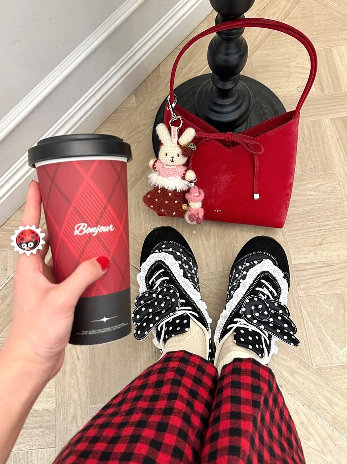 Top-down outfit view of black polka dot lace wing bow ballet flats with red plaid pants, coffee cup, and red charm handbag