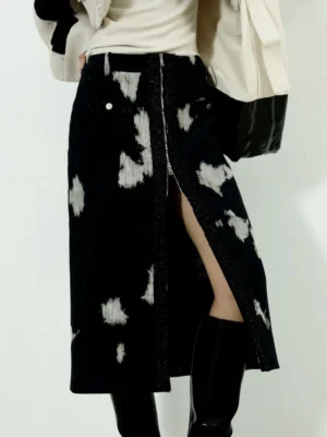Close-up view of black printed corduroy midi skirt with central front zipper slit and decorative pocket buttons