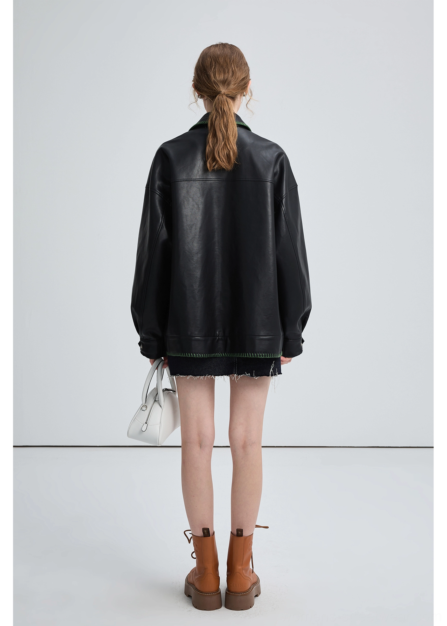 Black PU leather biker jacket featuring relaxed fit, utility pockets, snap details, and green collar stitching