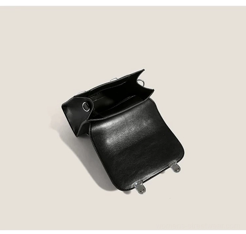 Open black PU mini satchel showing zippered main compartment, polyester lining, interior pocket, flap closure, and bottom studs