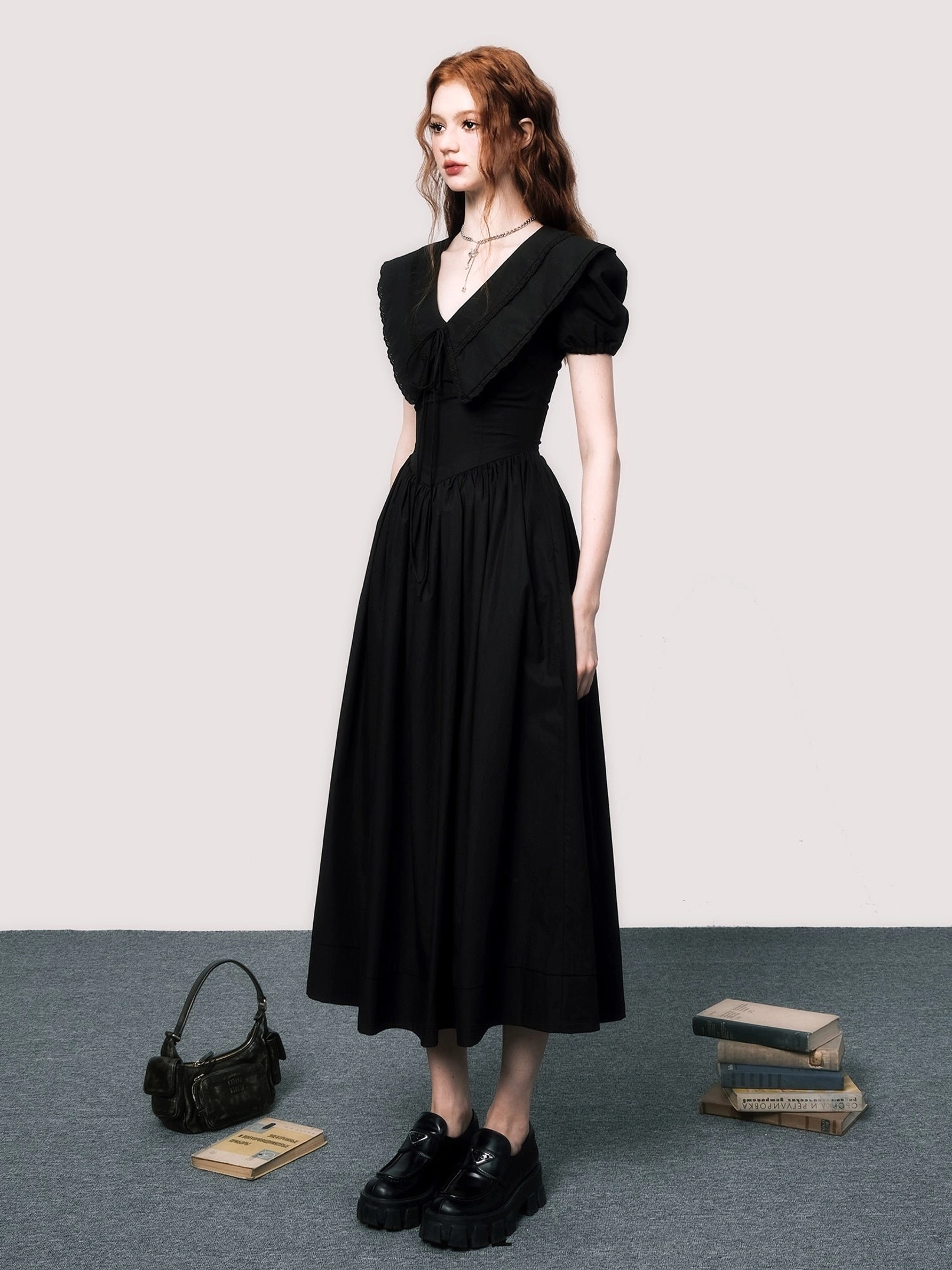 Side view of black V-neck puff sleeve midi dress styled with black loafers and showing its high-waisted A-line silhouette