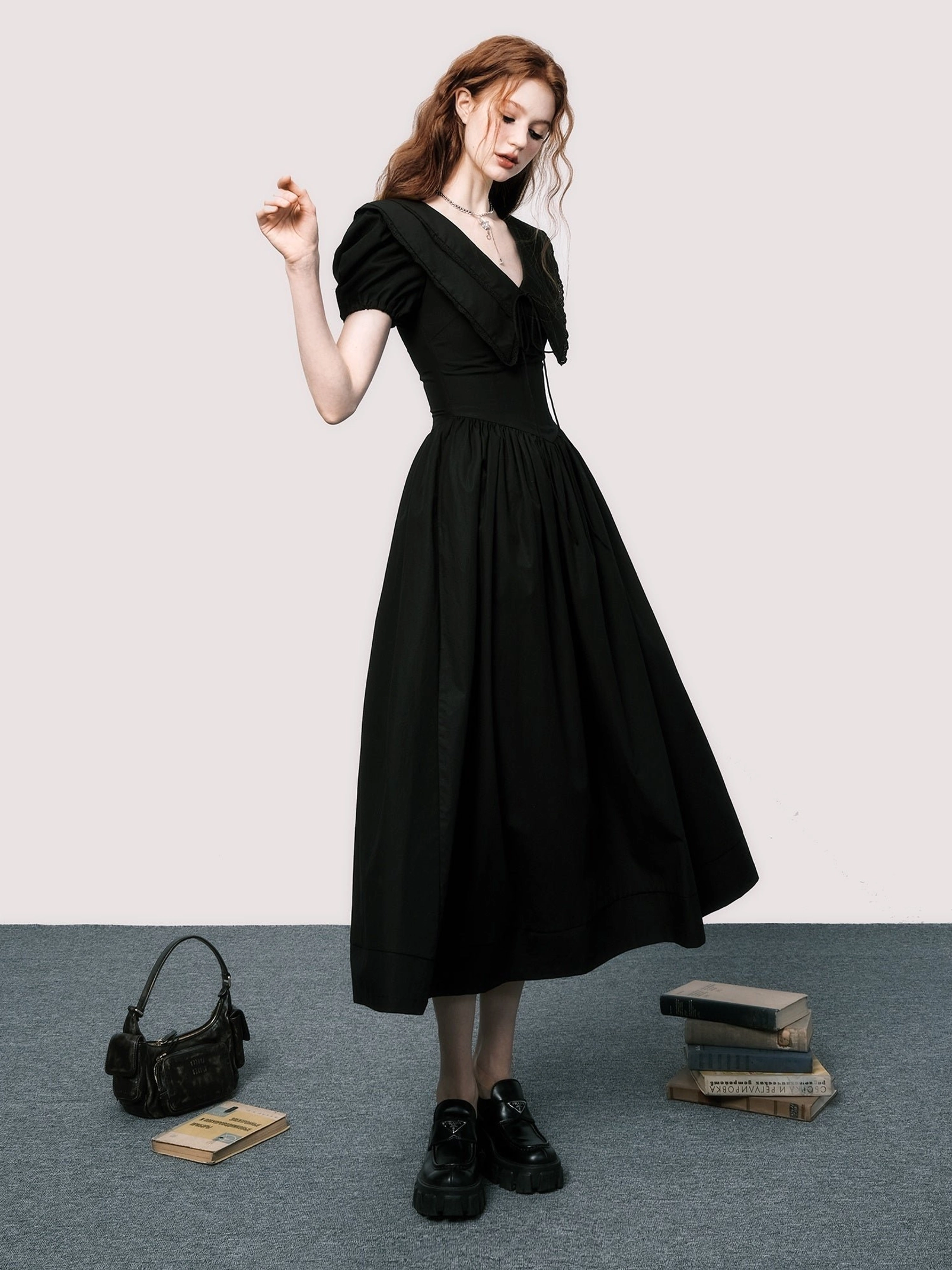 Front three-quarter view of black puff sleeve midi dress with V-neckline, defined waist, and flowy A-line skirt