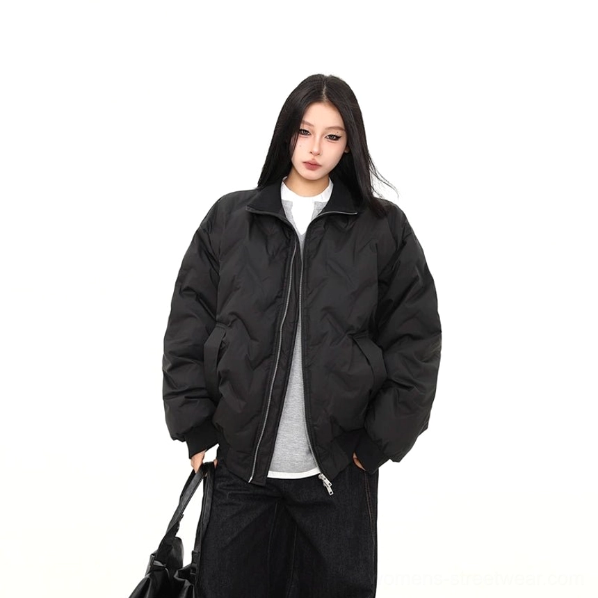 Close-up of black oversized puffer bomber jacket with silver zipper hardware, matte fabric, side pocket, and chevron quilting