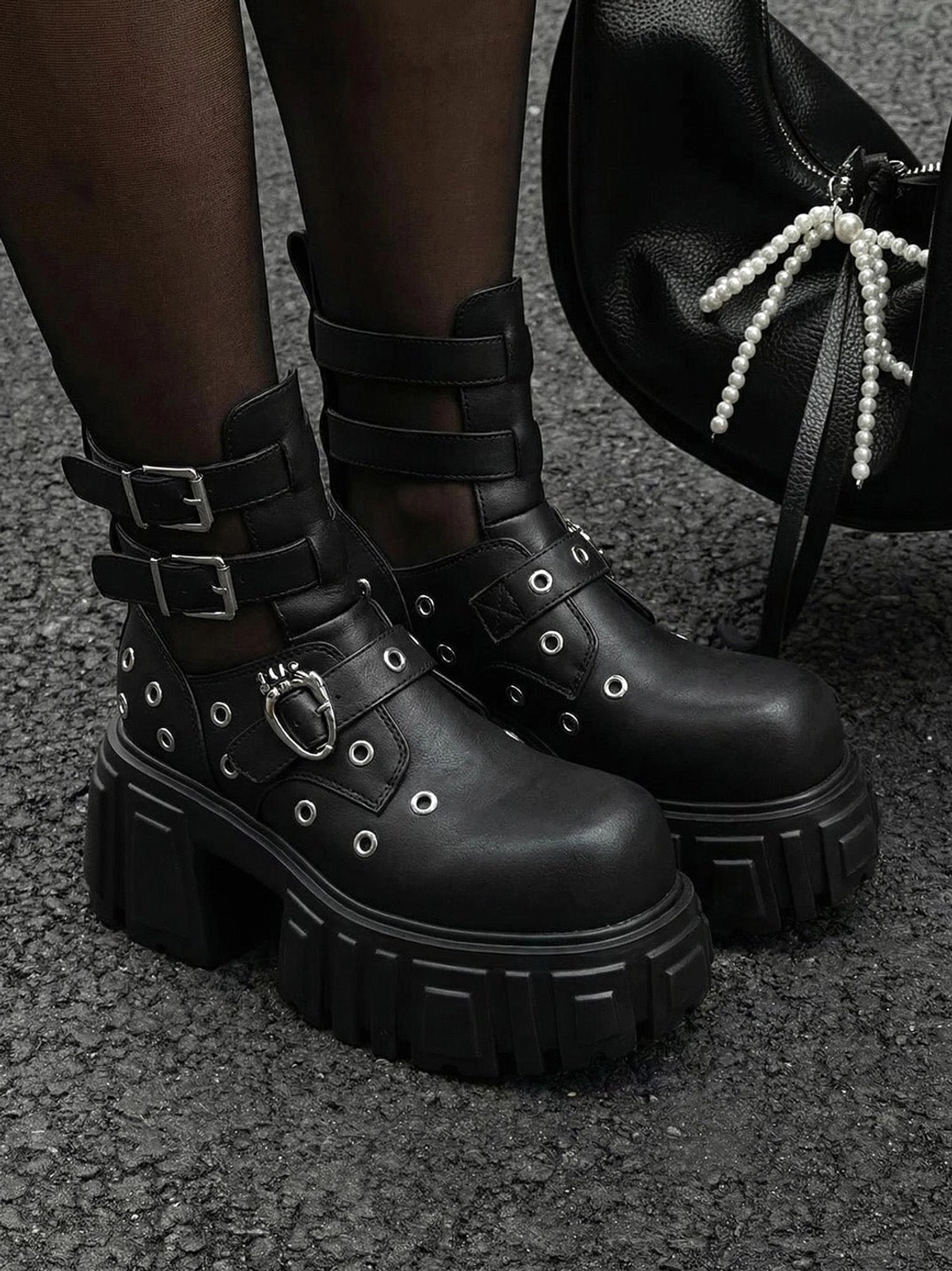 Street style model wearing black punk cutout platform boots with sheer stockings and a pearl handbag in an alternative fashion outfit