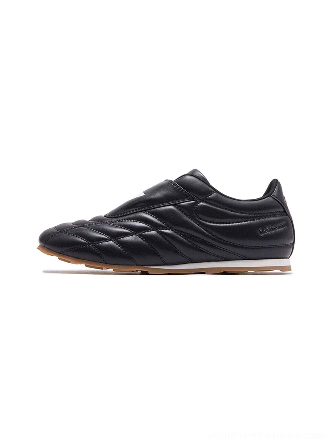 Black quilted leather soccer trainer sneaker with adjustable strap, white tongue patch, and gum rubber outsole on a white studio background