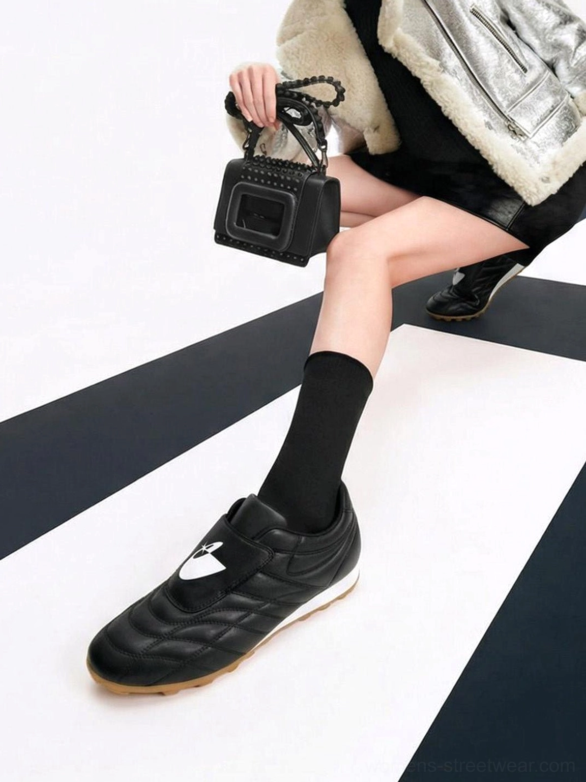 Black quilted soccer sneakers with adjustable strap and gum sole styled with black socks on a checkered floor