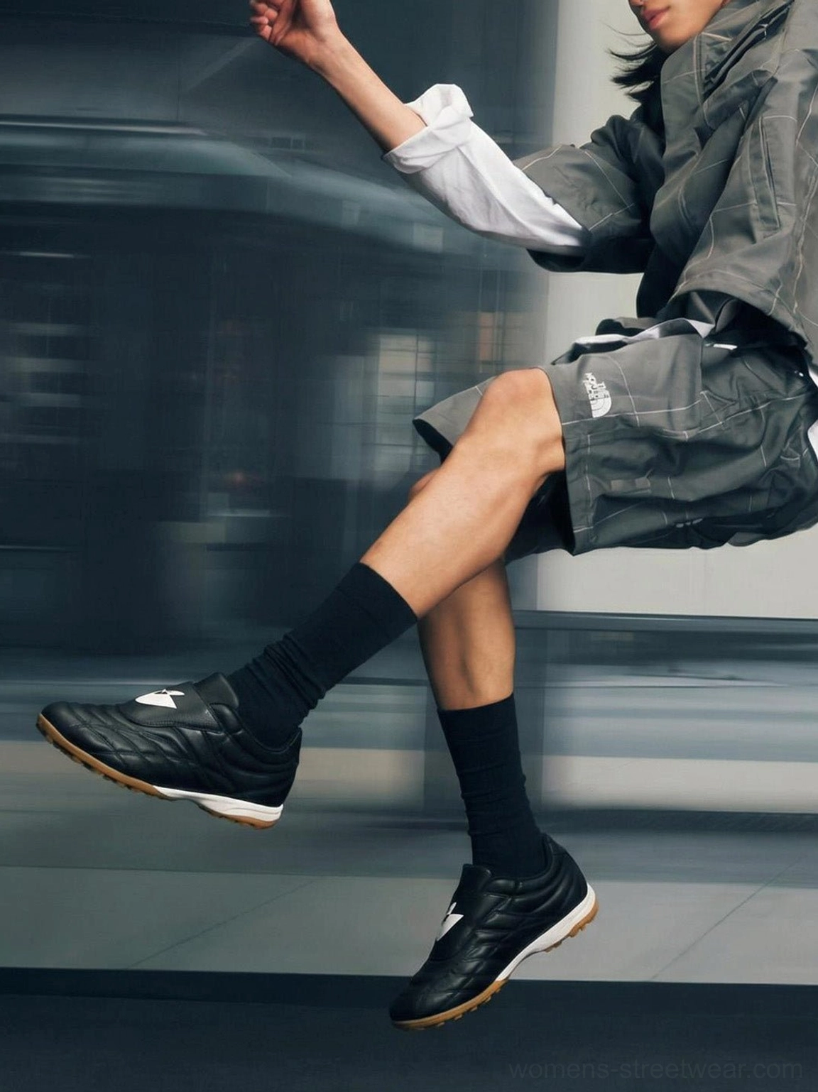 Black quilted leather soccer trainer sneakers worn with a grey sports outfit in an urban indoor passage