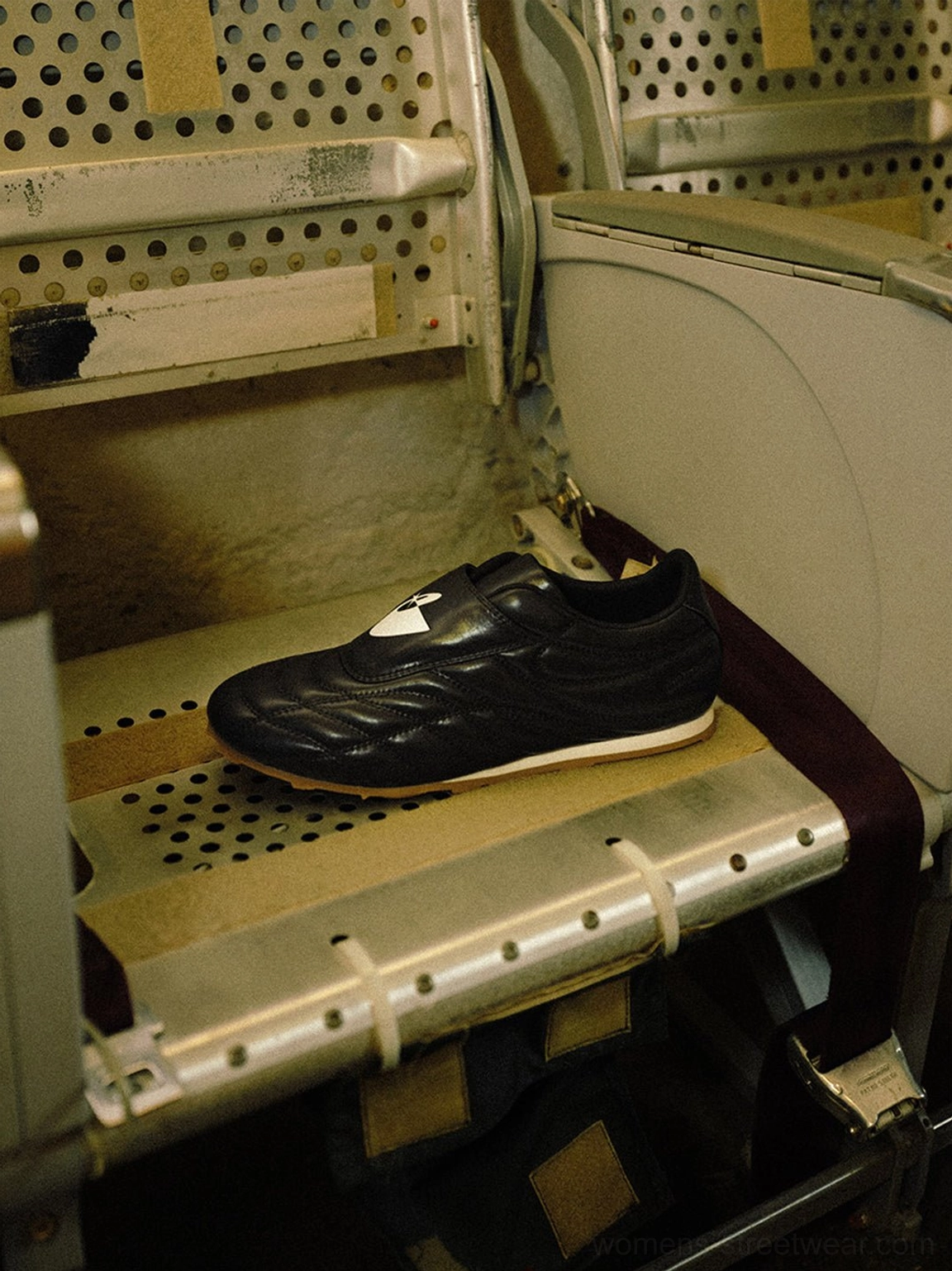 Black quilted soccer training sneaker displayed inside a metal gym locker with its low-profile silhouette visible