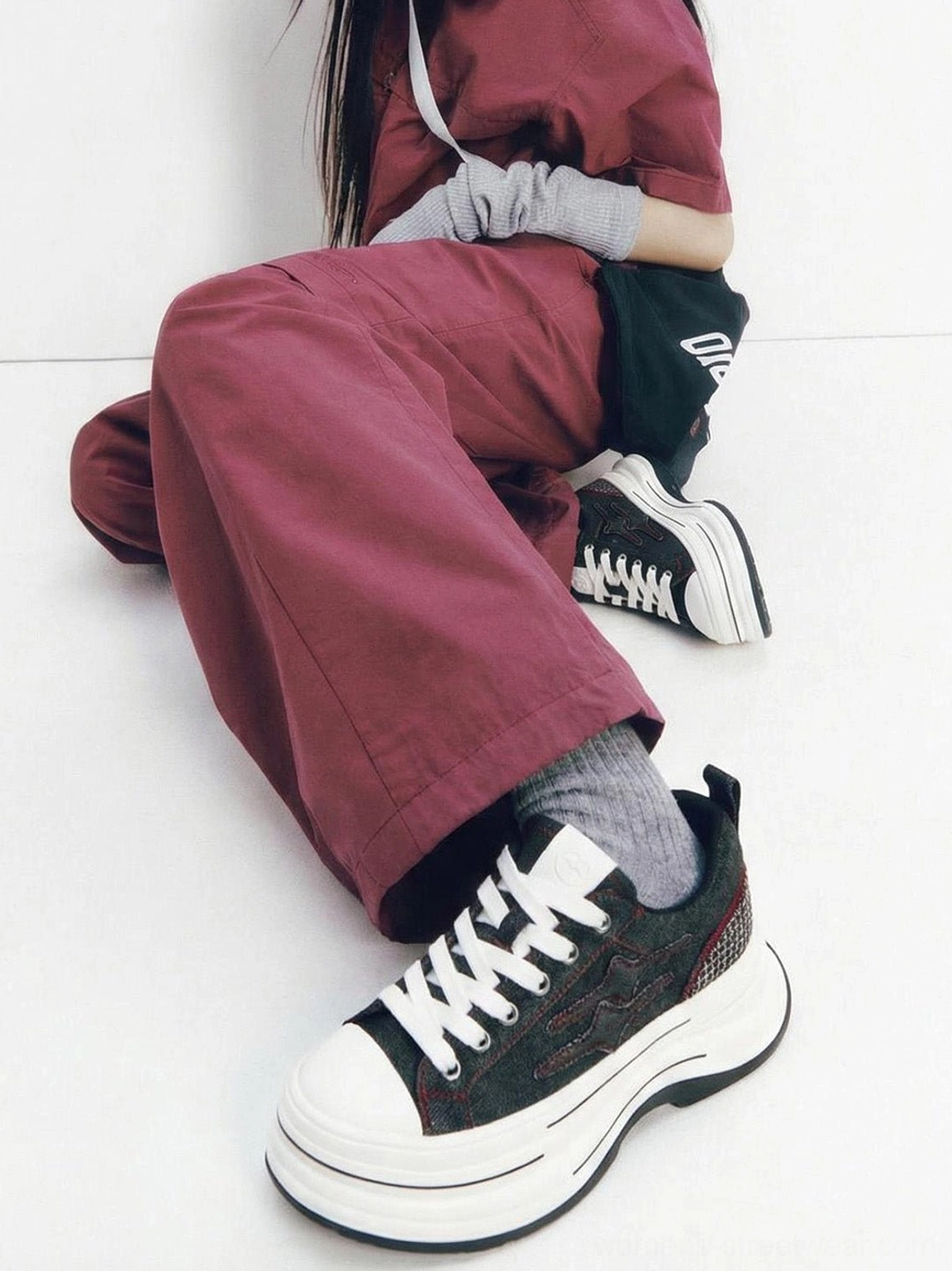Black red chunky canvas platform sneakers displayed with burgundy wide leg trousers, grey socks, white laces, and layered midsoles