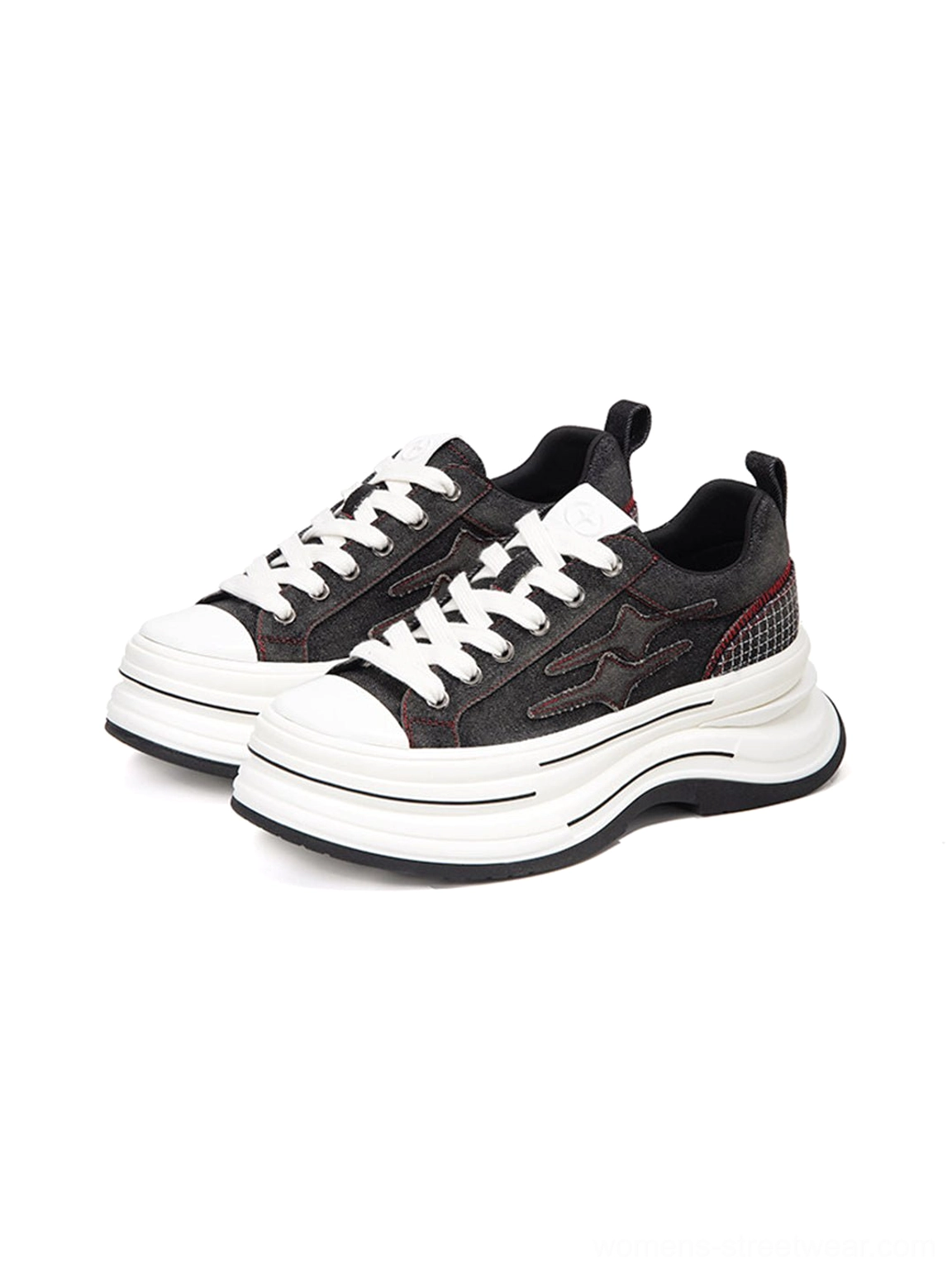 Three quarter view of black red platform canvas sneakers showing layered thick midsole, dark upper, red heel stitching, and contrasting white details