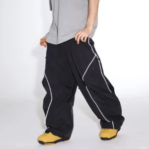 Black reflective piped baggy snowboard cargo pants styled with yellow ski boots in a low-angle streetwear outfit
