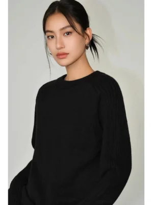 Black relaxed crew neck sweater with soft fuzzy knit texture, ribbed sleeves, and loose Korean streetwear fit on a female model
