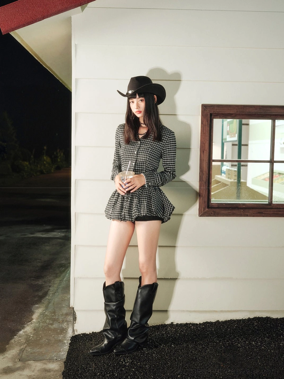 Three-quarter side view of black relaxed-shaft cowboy boots styled with a houndstooth two-piece streetwear look