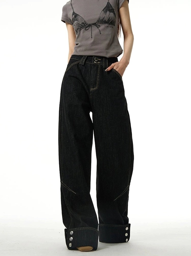 Front view of relaxed black wide-leg streetwear jeans featuring rolled button cuffs, classic waistband, and dark cotton denim