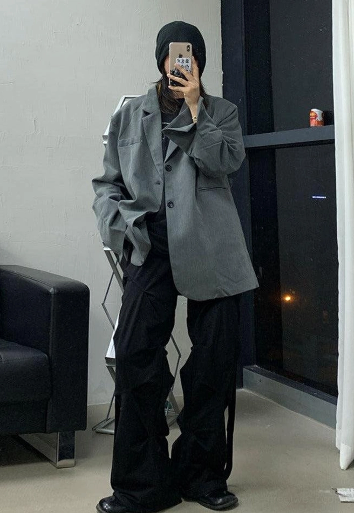 Black relaxed wide-leg streetwear pants styled with an oversized gray blazer in a modern casual indoor outfit