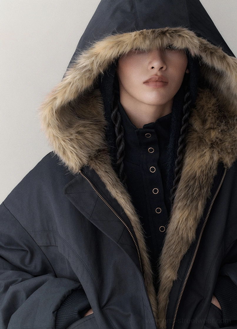 Front close-up of a black reversible faux fur winter jacket with fur-trimmed hood, smooth shell fabric, and high-neck styling