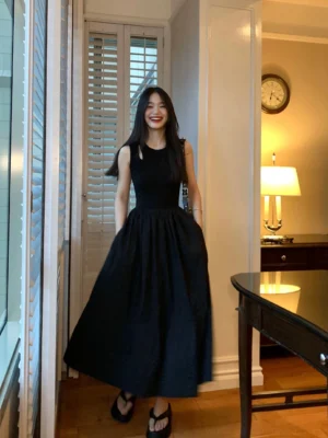 Front full-length view of black rib-knit drop-waist maxi dress with sleeveless fitted bodice and flowing gathered skirt
