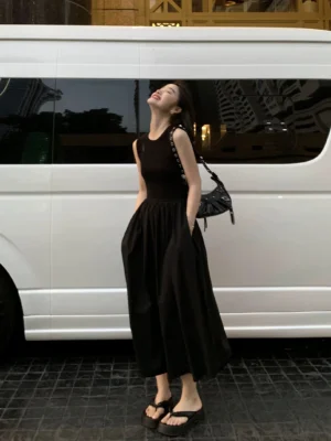 Three-quarter side view of black drop-waist maxi dress with rib-knit sleeveless bodice and side pockets