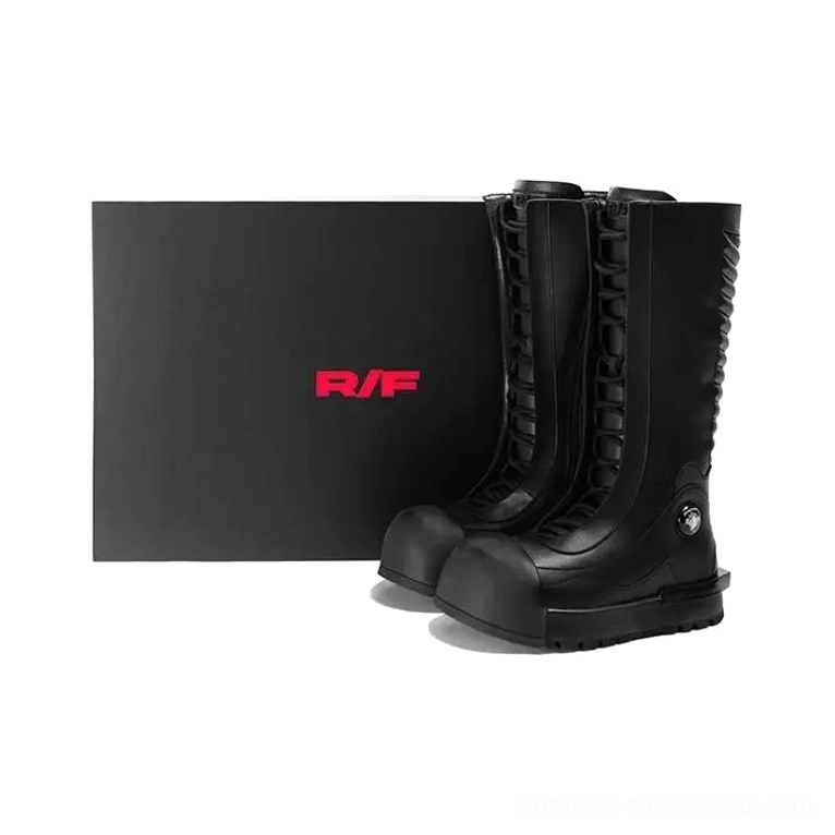 Black ribbed knee-high platform combat boots displayed beside a retail packaging box, featuring lace-up front and chunky outsole