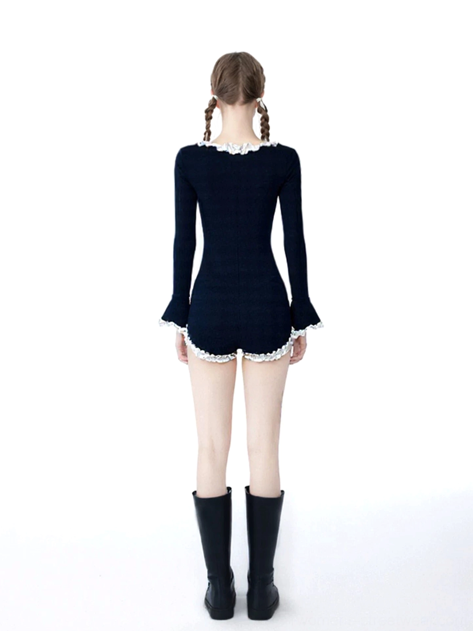 Back view of a fitted black ribbed knit romper with long sleeves, white ruffle cuffs, and high-cut leg trim