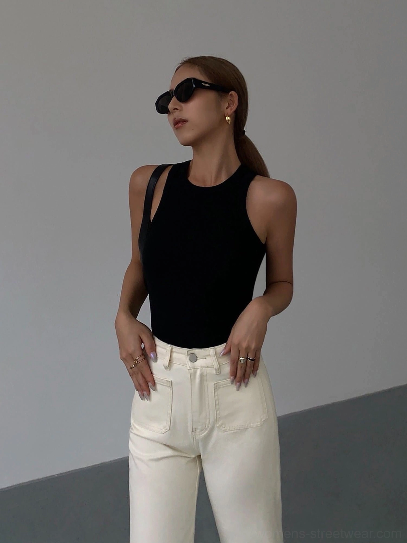 Black ribbed knit tank top full front half-body view on female model with black sunglasses, styled with off-white jeans on minimalist background