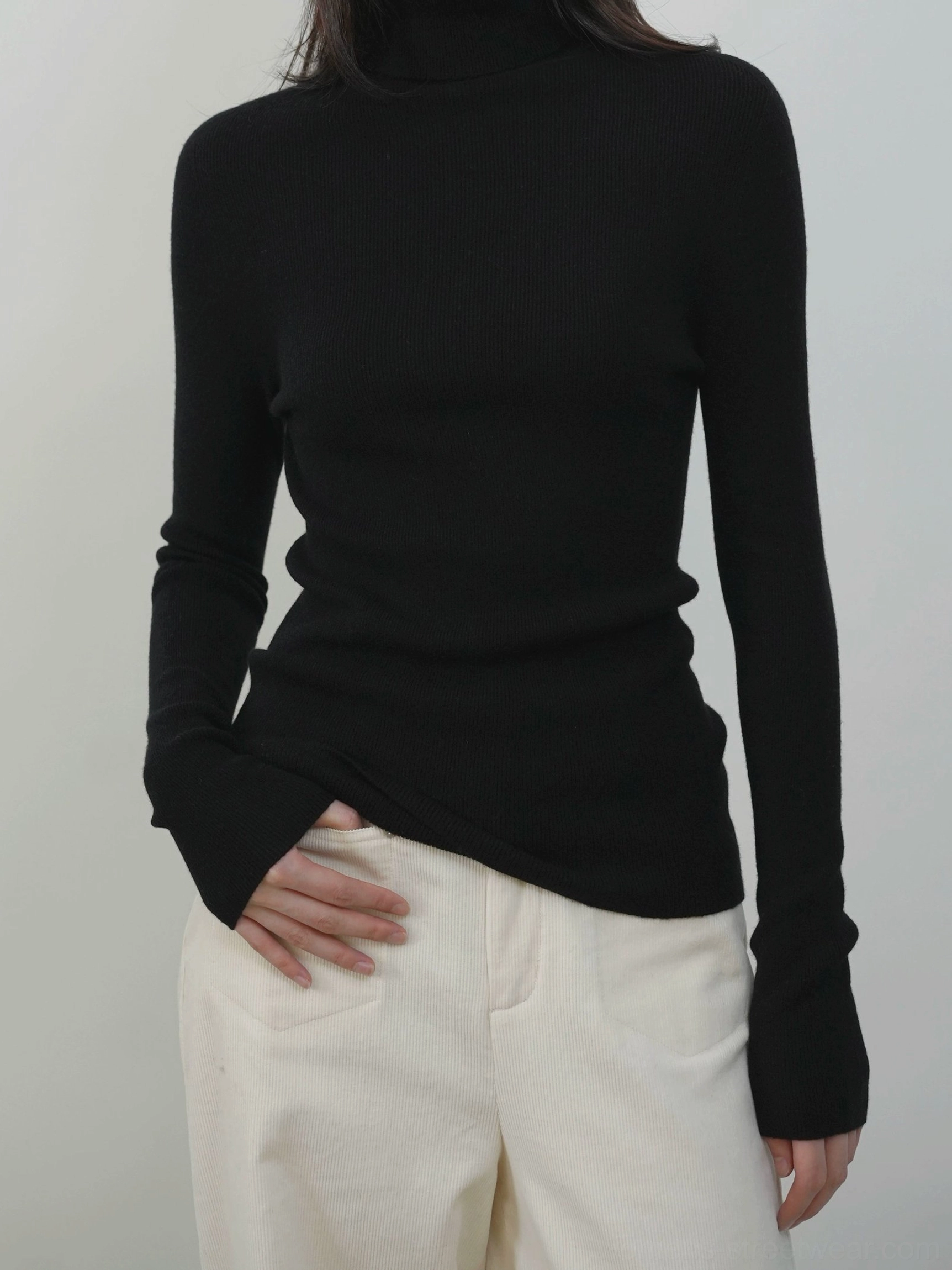 Black ribbed mock neck knit sweater for women worn with off white casual trousers in a slim streetwear outfit