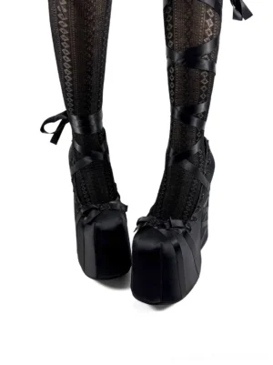 Black ribbon lace platform pumps worn with patterned fishnet thigh-high stockings, satin toe bows, and ribbon ankle ties