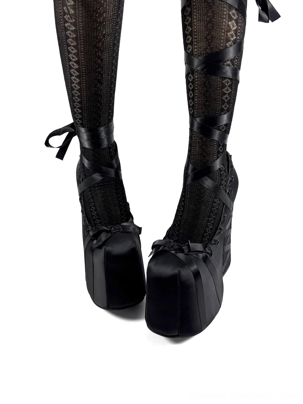 Black ribbon lace platform pumps worn with patterned fishnet thigh-high stockings, satin toe bows, and ribbon ankle ties