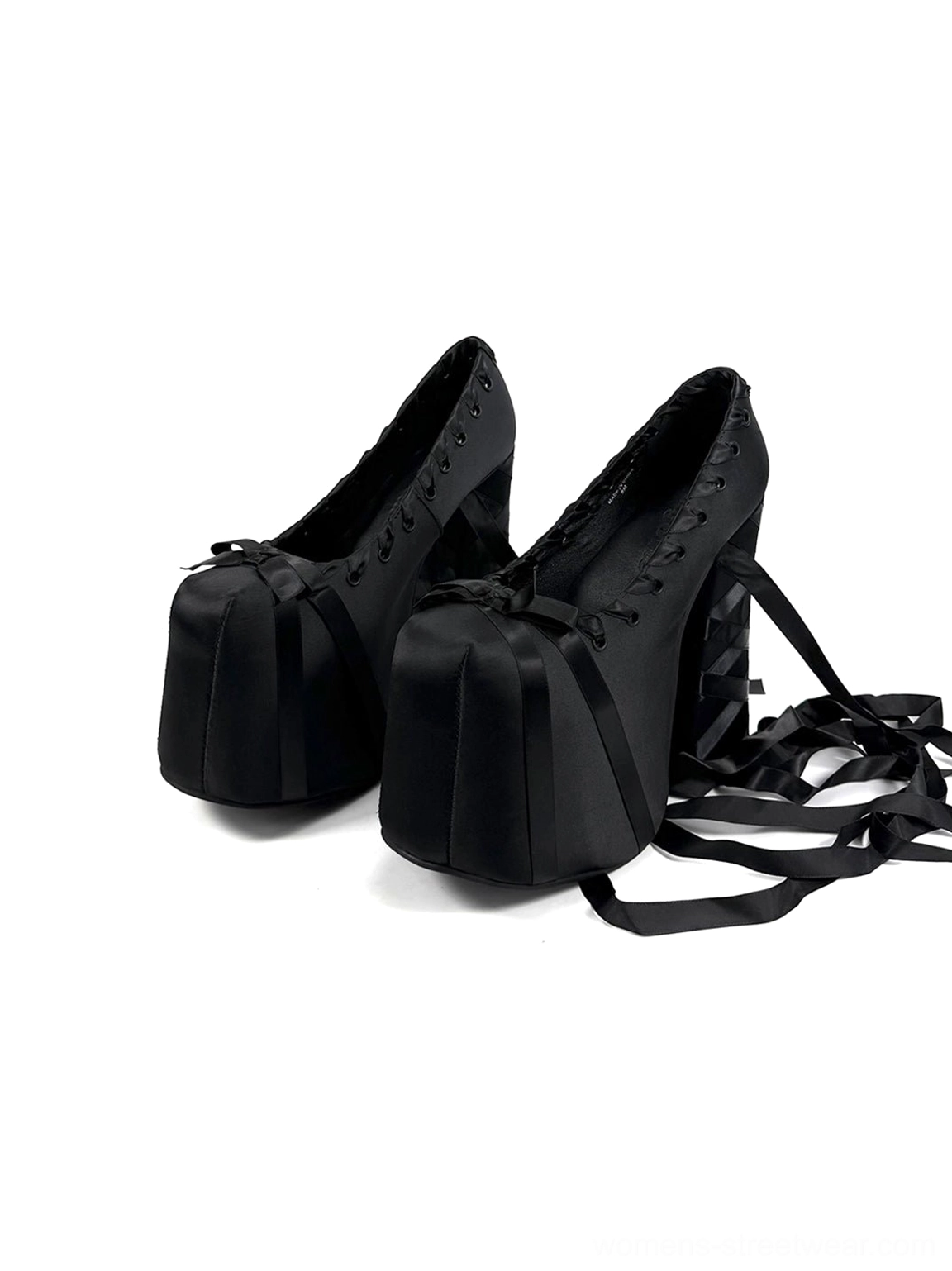 Pair of black ribbon lace platform pumps displayed from the side with lace-up fronts, wrapped block heels, and trailing ribbons