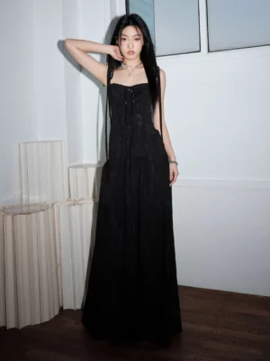 Front full-body view of a black ribbon-strap corset maxi dress with lace-up bodice, textured fabric, fitted waist, and flowing floor-length A-line skirt