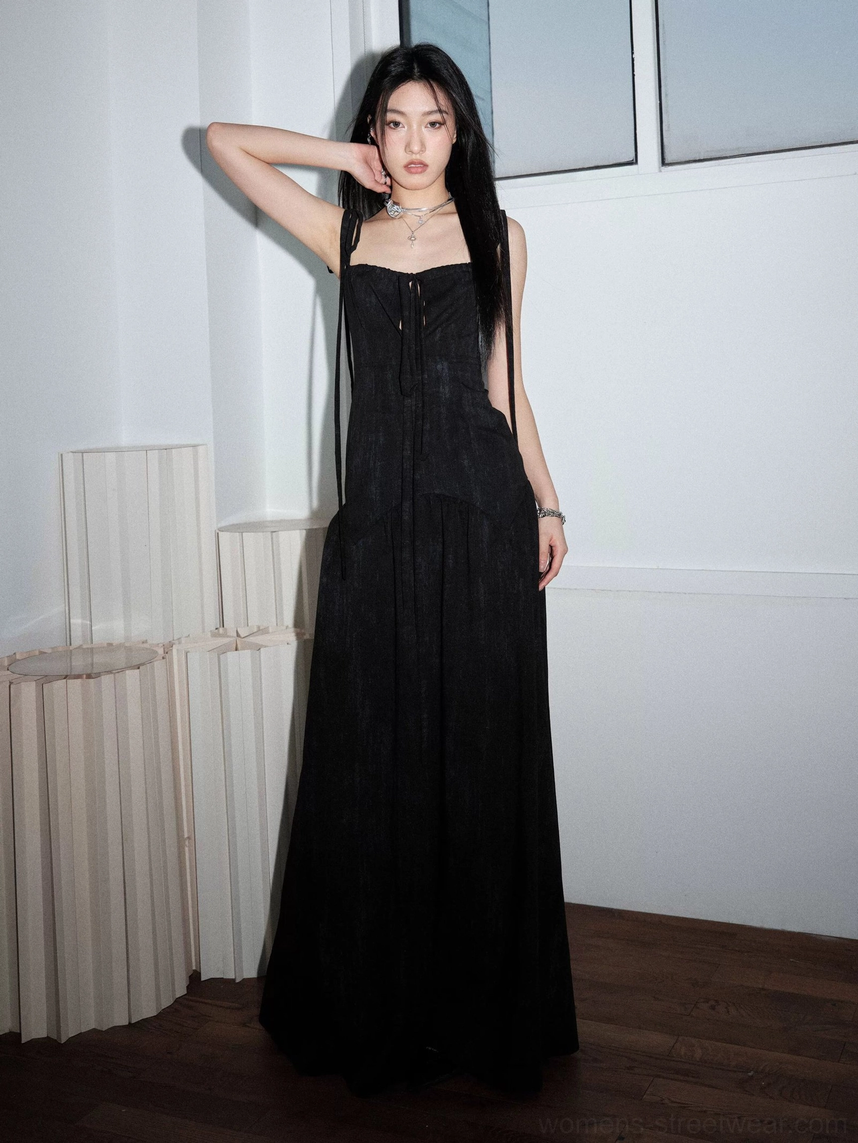 Front full-body view of a black ribbon-strap corset maxi dress with lace-up bodice, textured fabric, fitted waist, and flowing floor-length A-line skirt