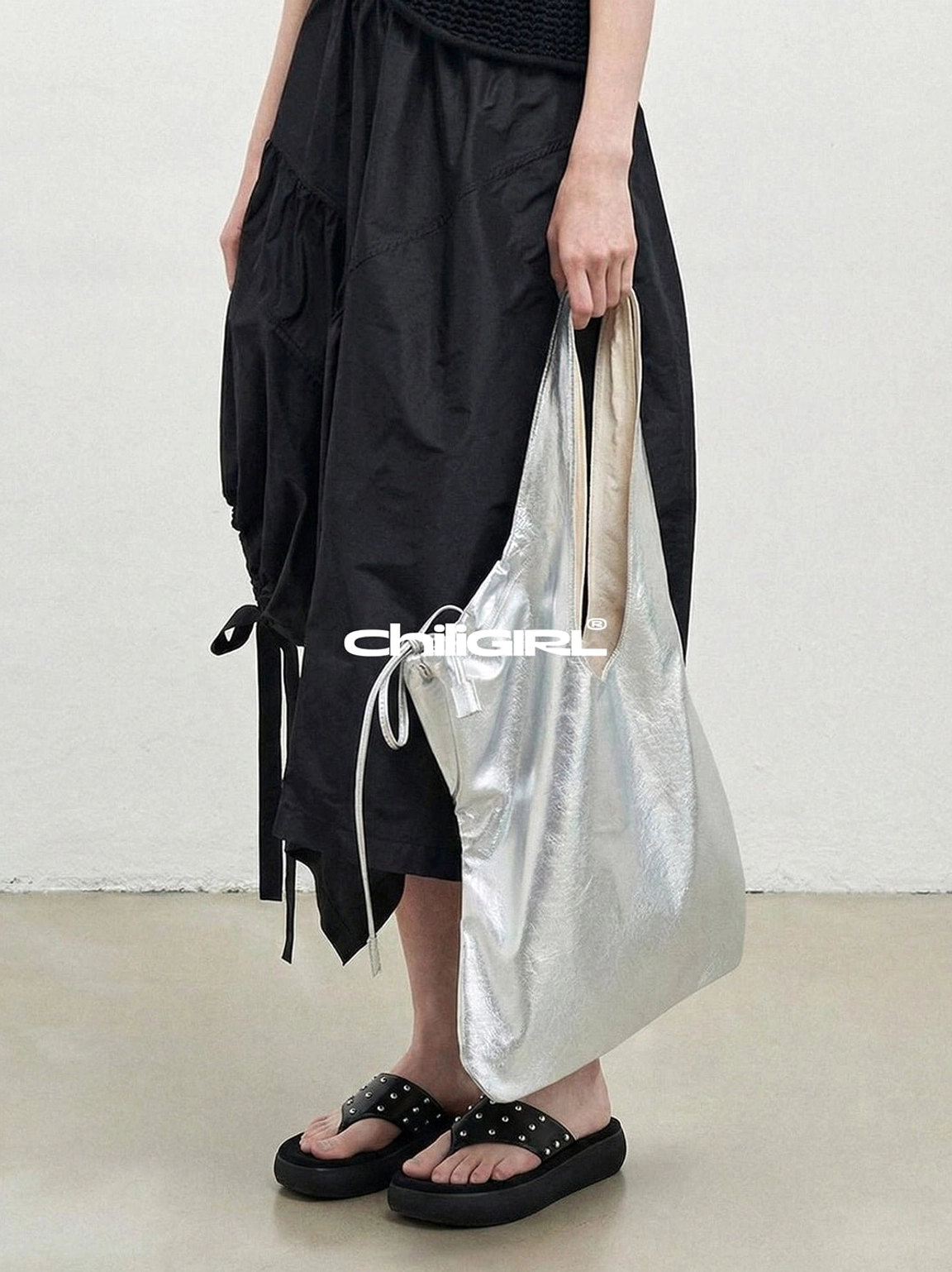 Black rivet platform sandals paired with a black ruffled midi dress and silver tote