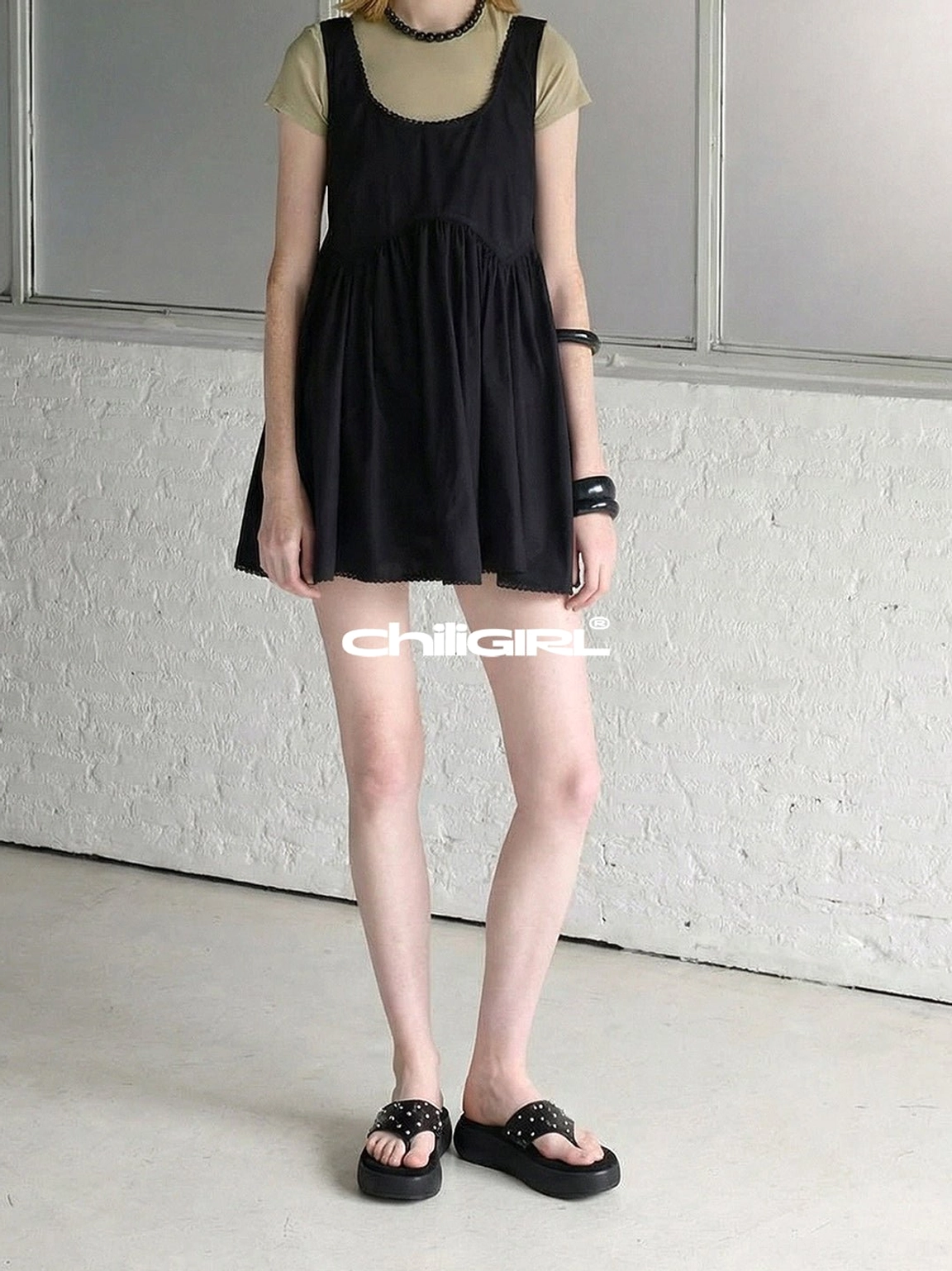 Black rivet platform thong sandals completing a minimalist outfit with a tiered mini dress