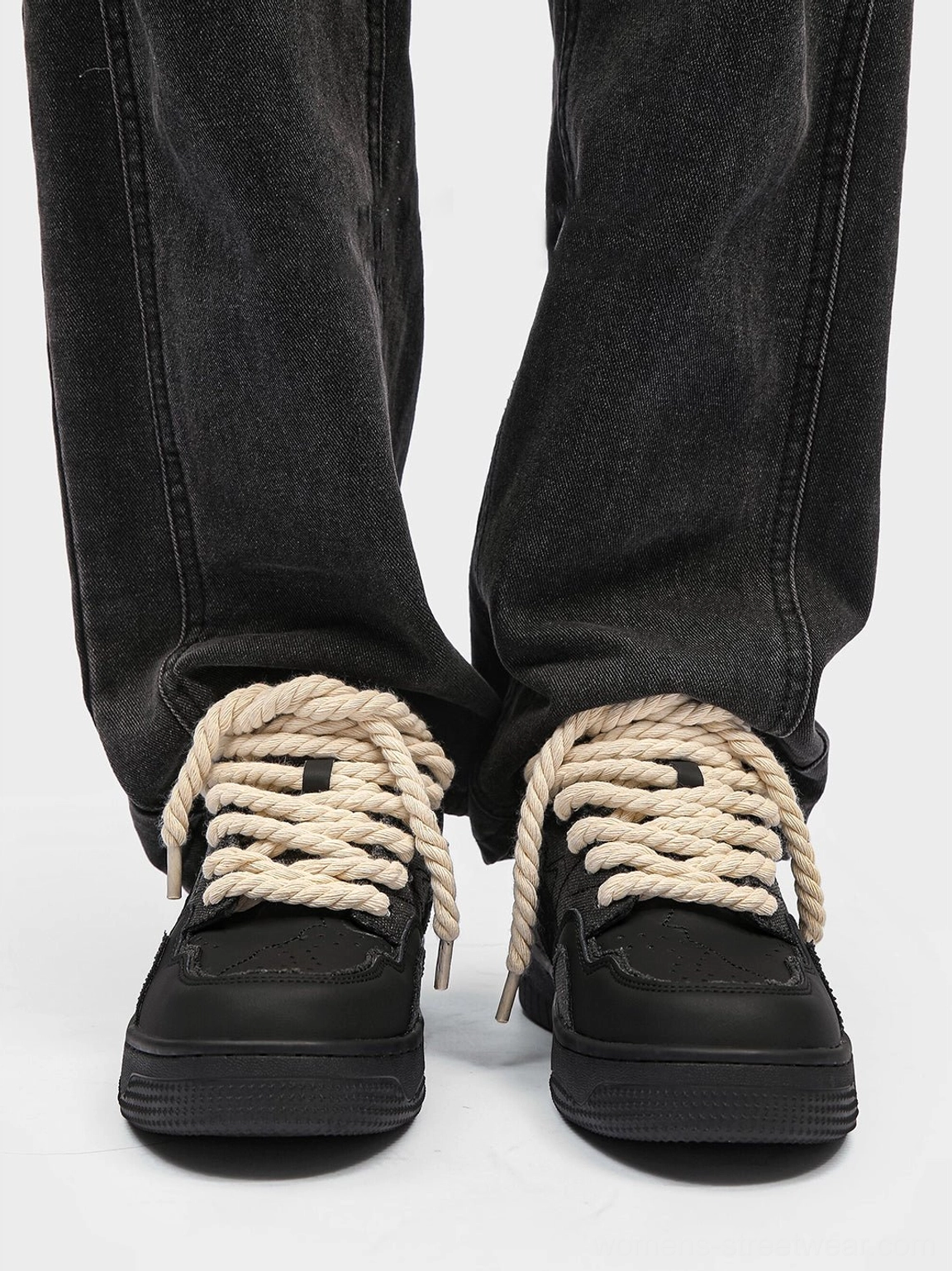 Front view of black rope lace low-top streetwear sneakers styled with dark gray straight-leg jeans