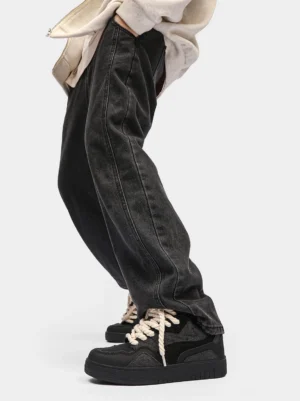 Black rope lace low-top streetwear sneakers worn with dark wash straight jeans in a casual street outfit
