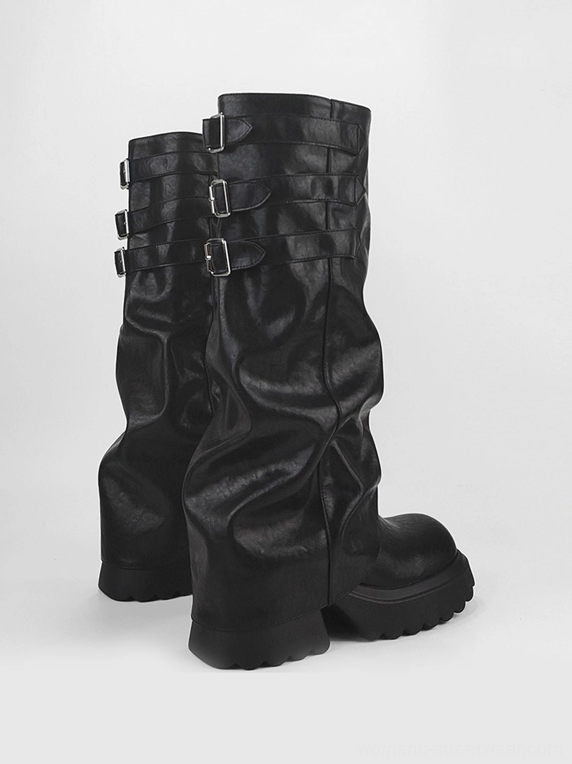 Pair of black ruched buckle knee-high chunky platform boots with thick lug soles in front three-quarter view