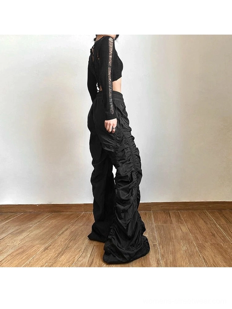 Black ruched high-waist wide-leg streetwear pants shown from the side back with glossy fabric and floor-length drape
