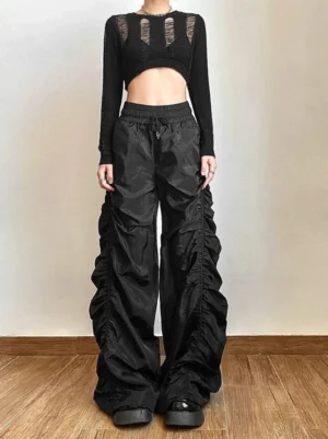Black ruched high-waist wide-leg streetwear cargo pants styled with a black cutout cropped knit top in a full-body front view