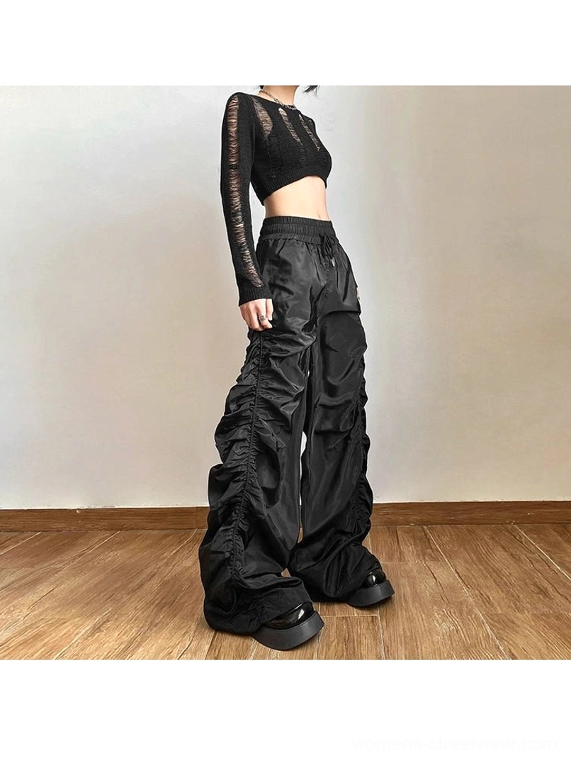 Black ruched high-waist wide-leg streetwear pants styled with a cropped knit top and platform shoes from an angled front view