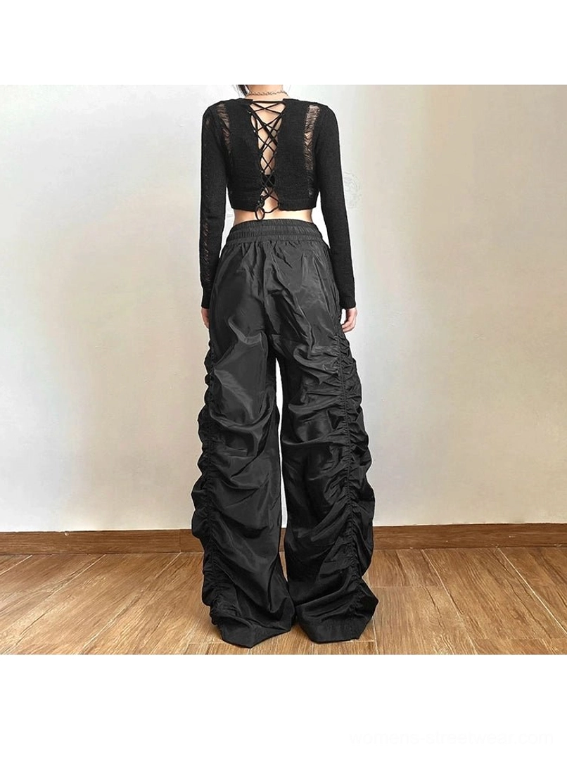 Back view of black ruched high-waist wide-leg streetwear pants with floor-length silhouette and adjustable drawstring waist