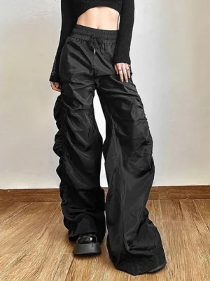 Black ruched high-waist wide-leg streetwear pants shown from an angled side view with cropped long-sleeve top and platform loafers