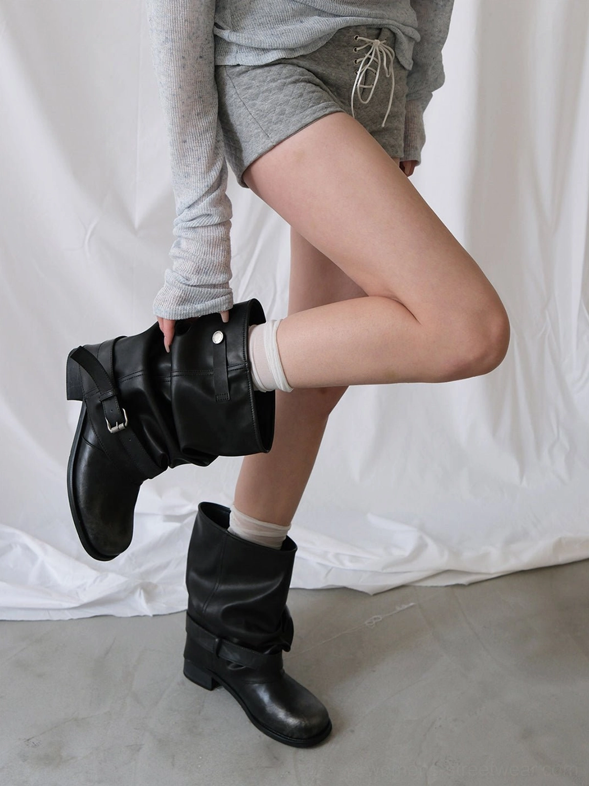 Black ruched mid-calf boots with metal buckle detail styled with white socks and casual Korean streetwear