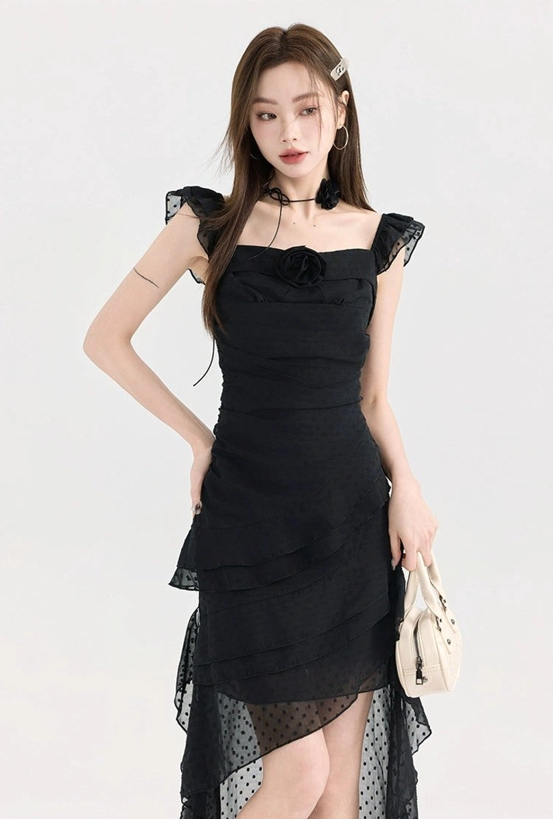 Close-up view of black ruffle high-low dress featuring a slim fitted bodice, square ruffle neckline, and sheer polka dot tulle asymmetrical hem